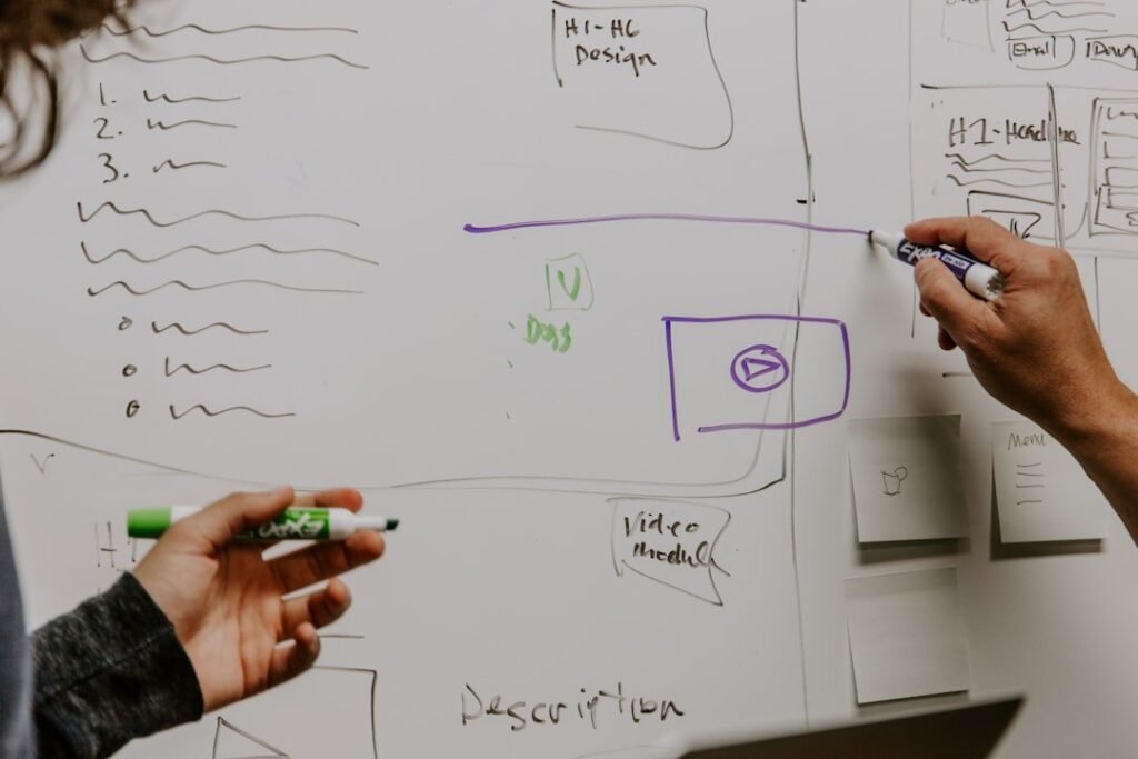Two colleagues mapping a data flow diagram on a whiteboard