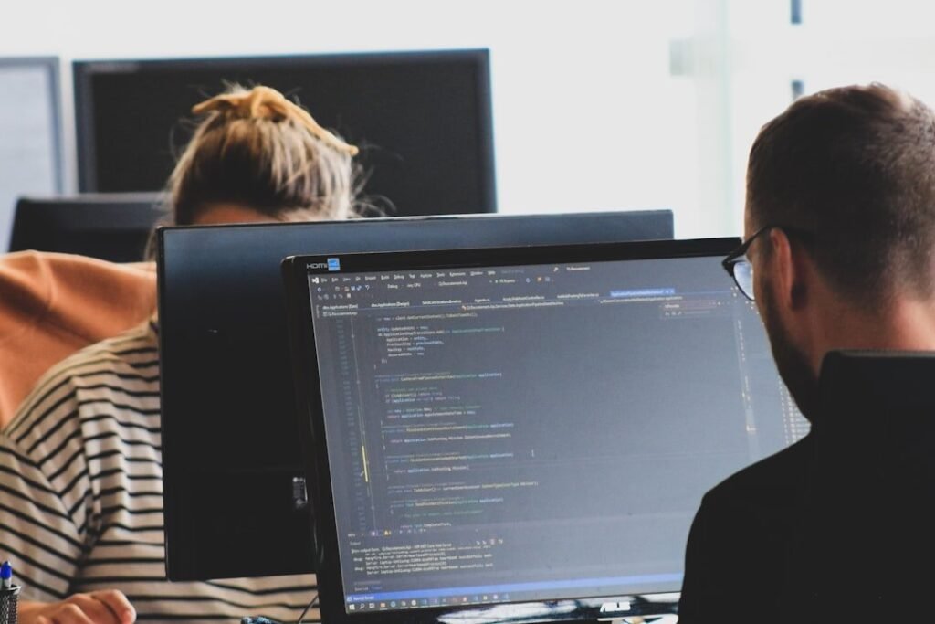 Two engineers reviewing code together at dual monitors