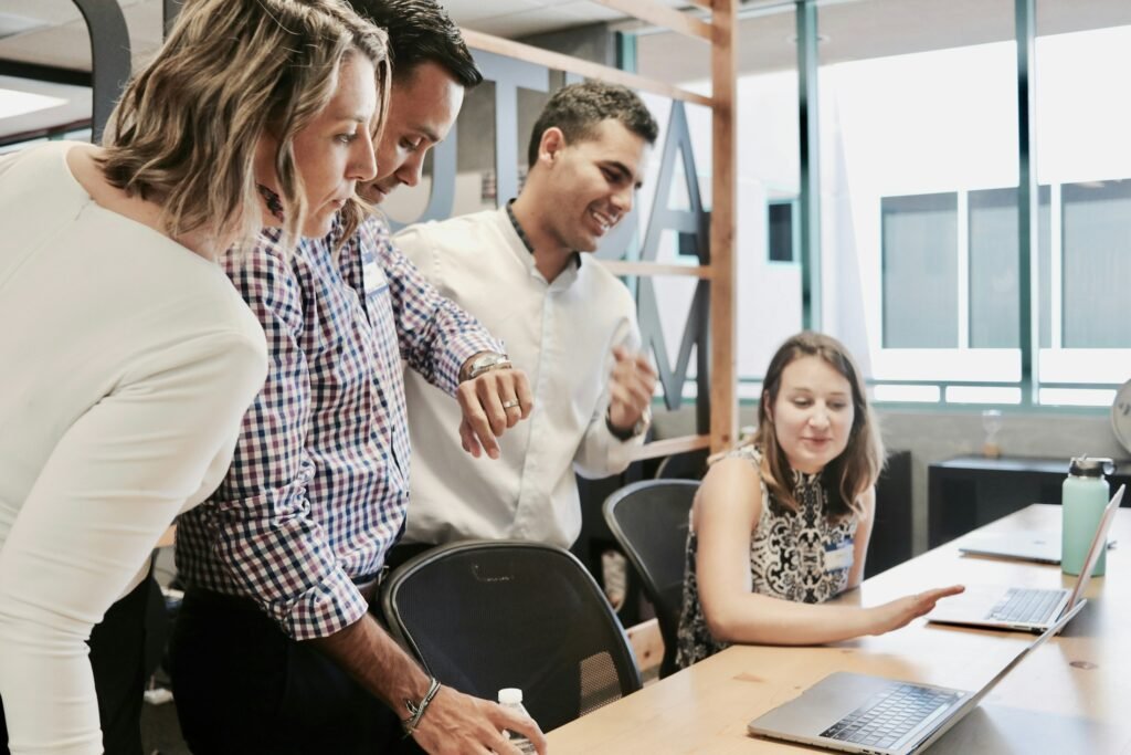 A small team gathered around a laptop working through a pipeline model together